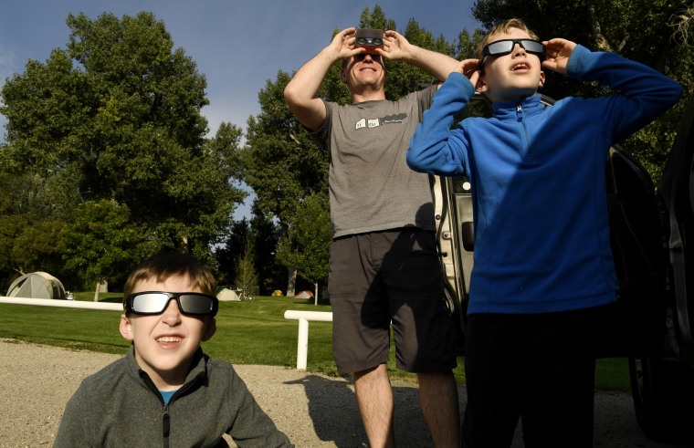 Image:Eric Romberg teaches his sons and Jarrett, 6, left, and John, 7, how to use their eclipse glasses at City Park
