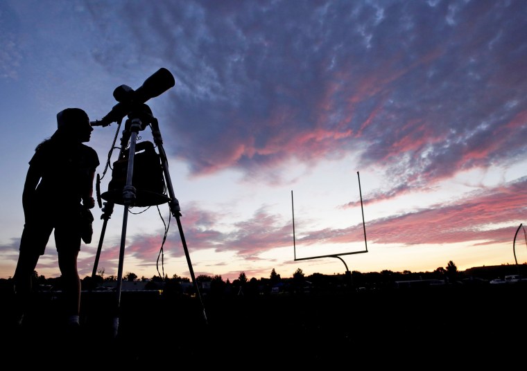 Image: A woman looks through a telescope on the football field at Madras High School the evening before a solar eclipse in Madras, Oregon
