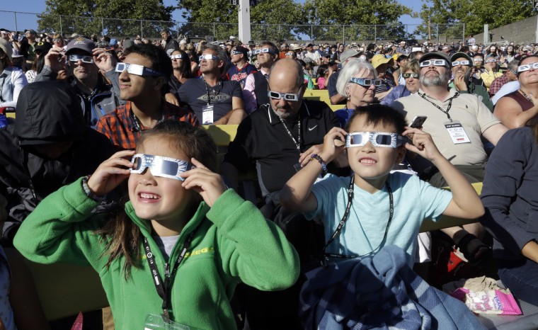 Image: A crowd wears protective glasses as they watch the beginning of the solar eclipse from Salem, Oregon