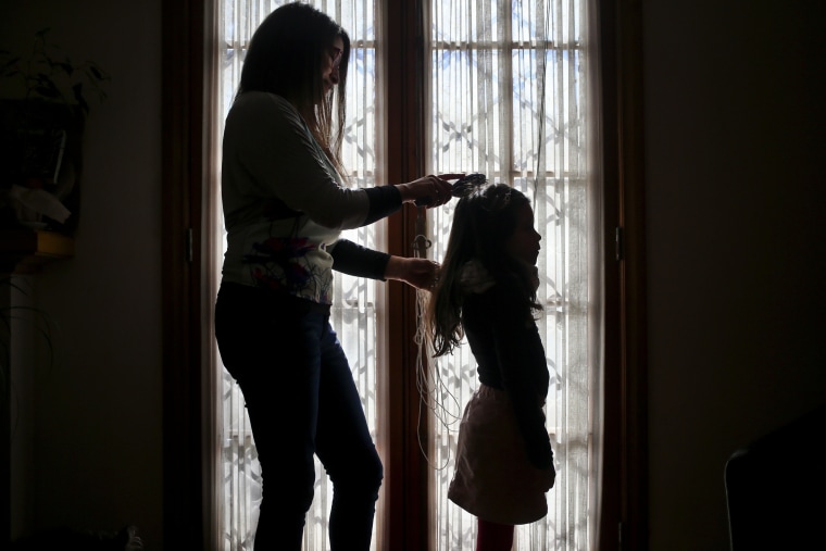 Image: Monica Flores combs her daughter's hair at their home