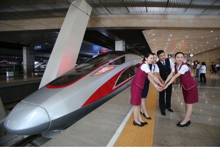 Railway workers pose next to one of China’s new bullet trains.