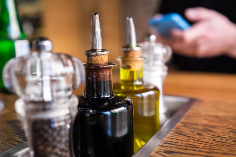 Close-Up Of Vinegar Bottles With Salt And Pepper Shaker On Table