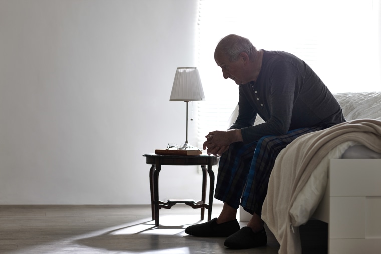 Image: Elderly Man Sitting on Bed Looking Serious