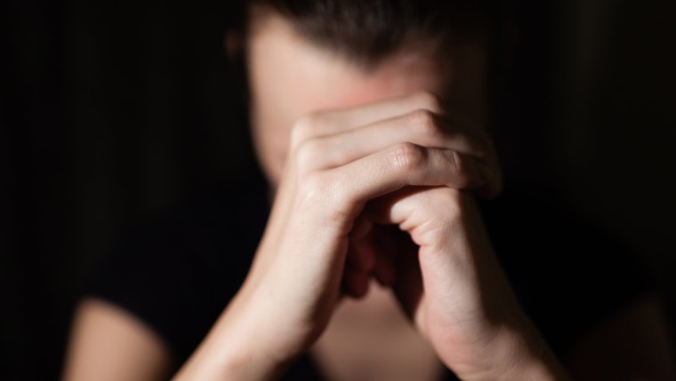 Image: A woman holds her hands to her head