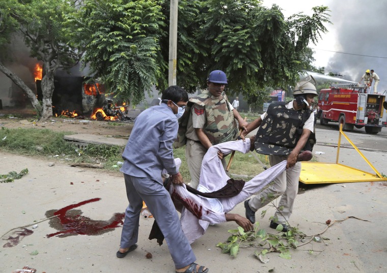 Image: Security officers carry the body of a man after riots broke out near a court in Panchkula