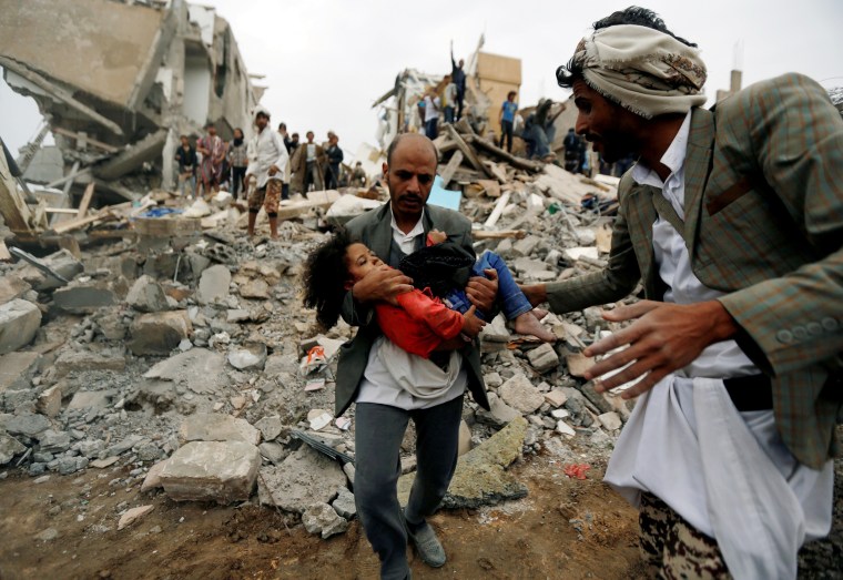 Image: Man carries an injured girl rescued from the site of a Saudi-led air strike in Sanaa
