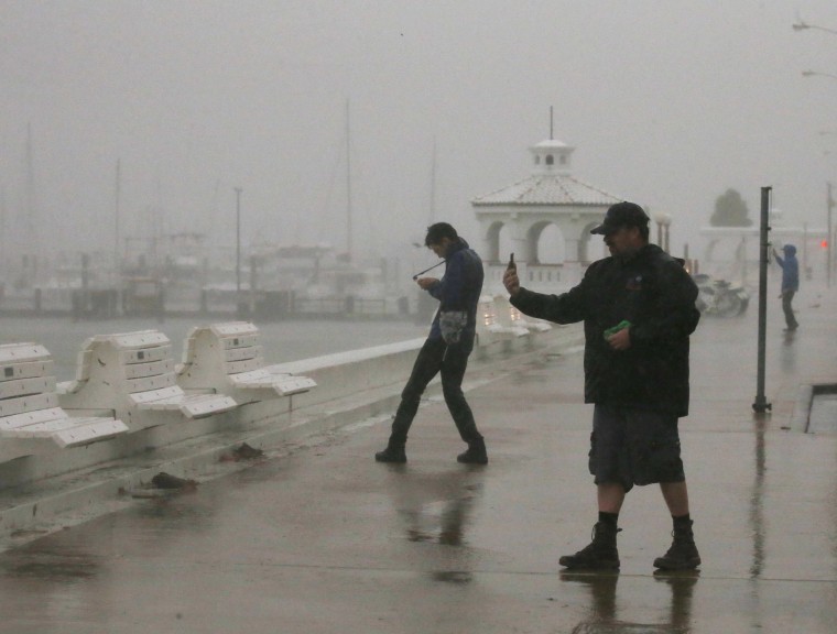 Image: A storm chaser films himself on a camera phone as Hurricane Harvey approaches, on the boardwalk in Corpus Christi