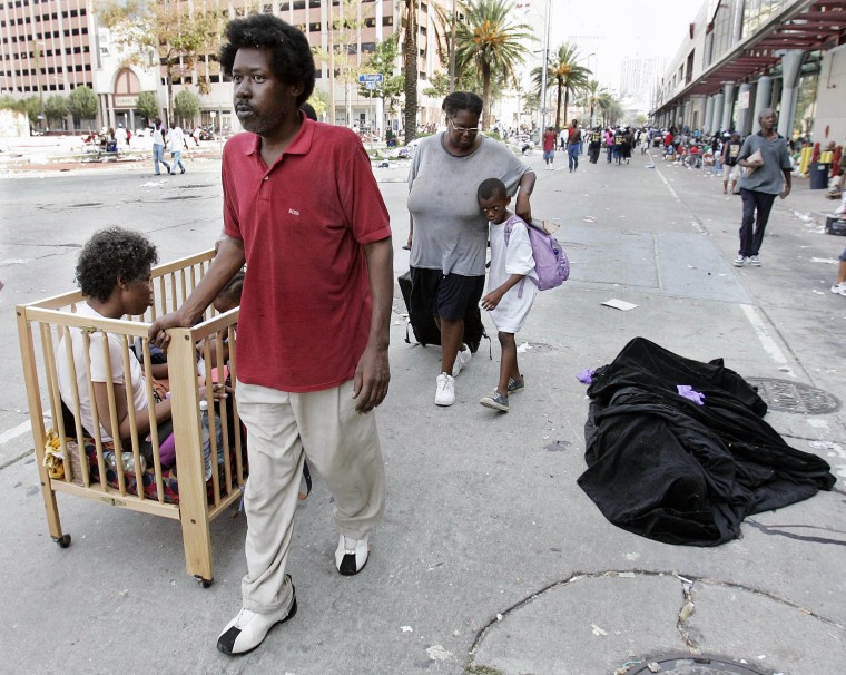 Image: A family of Hurricane Katrina victims walk past a covered body in front of the convention center in New Orleans