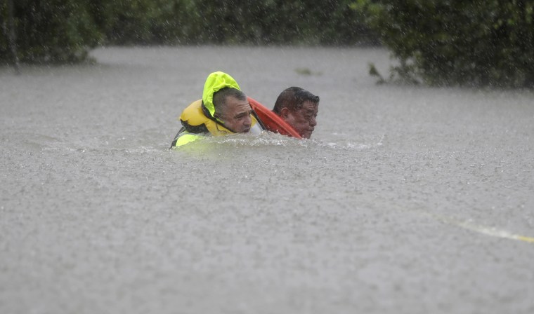 Image: Wilford Martinez, right, is rescued from his flooded car along Interstate 610 in floodwaters