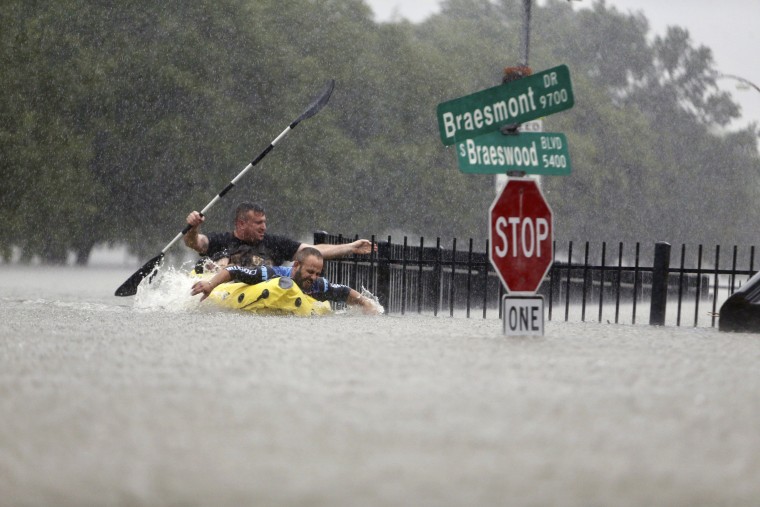 Image: Two kayakers try to beat the current pushing them down an overflowing Brays Bayou along S. Braeswood in Houston