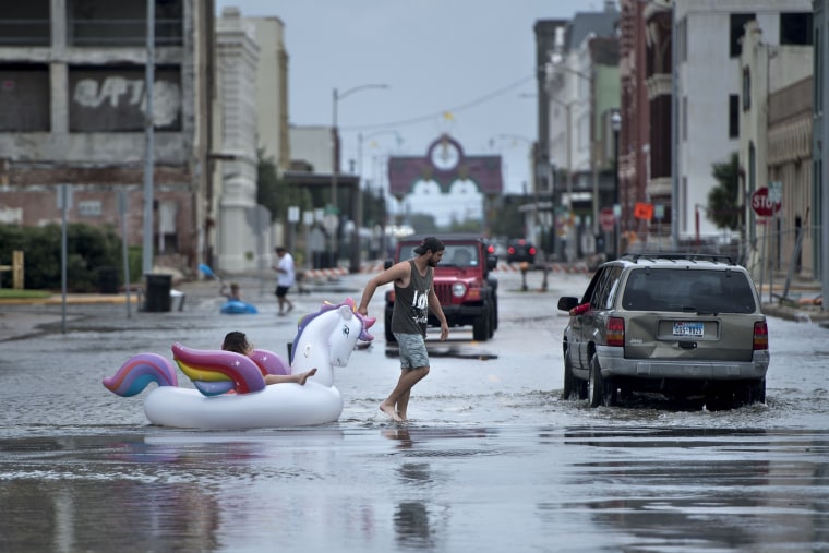 Image: People make their way down partially flooded roads following the passage of Hurricane Harvey