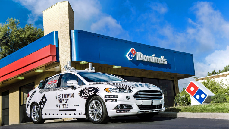 A Ford self-driving delivery vehicle is pictured in front of a Domino's pizza restaurant in this handout photo