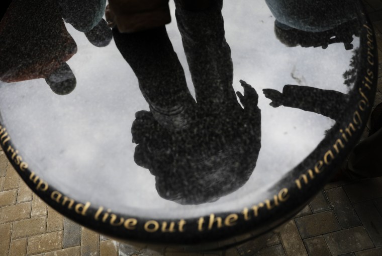 Image: A person reaches to touch the hand of a statue paying tribute to civil rights leader Martin Luther King Jr.