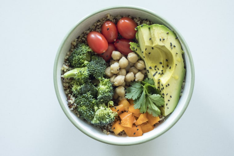 Image: A bowl of quinoa with avocado, cherry tomatoes, broccoli, orange peppers, chickpeas and cilantro.