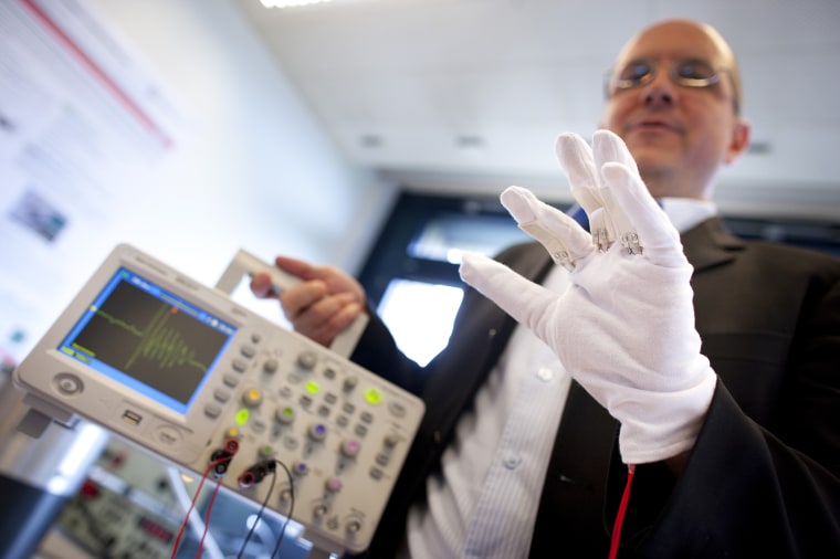 A scientist makes a demonstration of a piezoelectric energy harvesting glove during the media presentation of the Guardian Angels project at the Swiss Federal Institute of Technology in Ecublens
