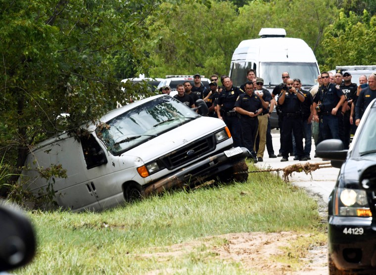 Image: Police investigators watch as the van containing the six members of the the Saldivar family who died is towed to the road