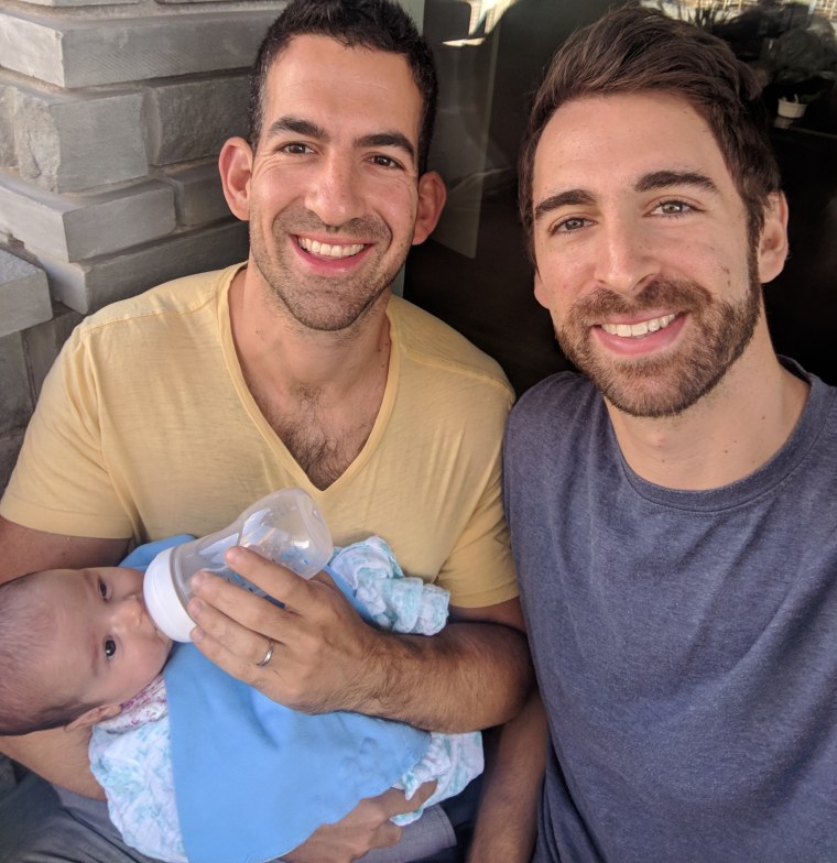 David Bledin (left) and his husband, Bart Rosenthal, holding their newborn, Sloane.