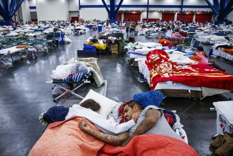 Image: A couple sleeps on cots at the convention center in Houston