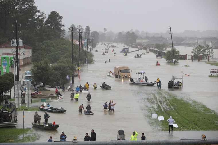 Image: People walk down a flooded street as they evacuate their homes from flooding caused by Hurricane Harvey