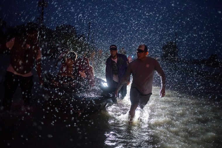Image: Samaritans help push a boat with evacuees to high ground during a rain storm caused by Tropical Storm Harvey along Tidwell Road in east Houston