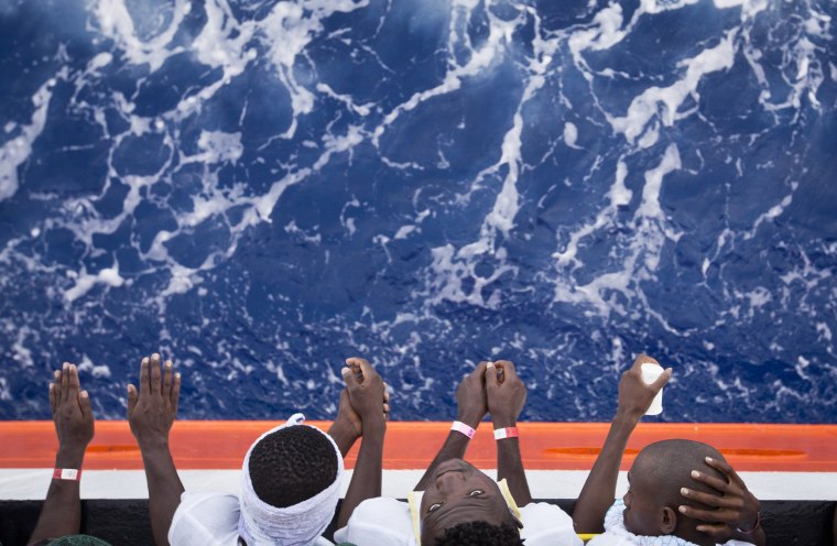 Image: African migrants stand on the deck of a rescue vessel in the Mediterranean Sea