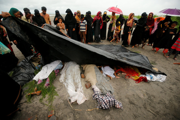 Image: People cover the bodies of Rohingya refugee women and children who died after their boat capsized while crossing the border through the Bay of Bengal, at Shah Porir Dwip, near Teknaf