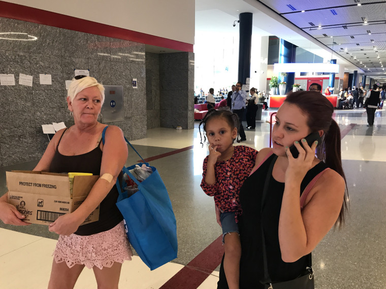 Image: Madison Gingrow, 21, holds her daughter Aleiyah, 3, and walks with her mom, Rene Farrell, 50, right, at the George R. Brown Convention Center as they try to find funds to relocate after Hurricane Harvey, Sept. 1, 2017.