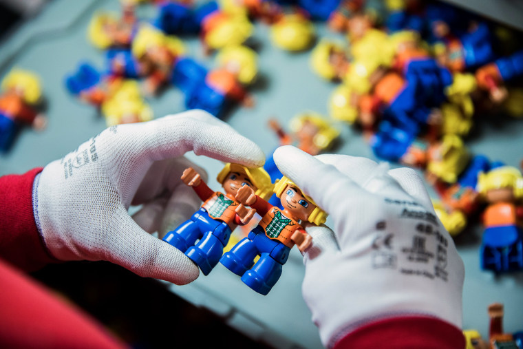 Image: An employee performs a quality control inspection on Lego Duplo figurines