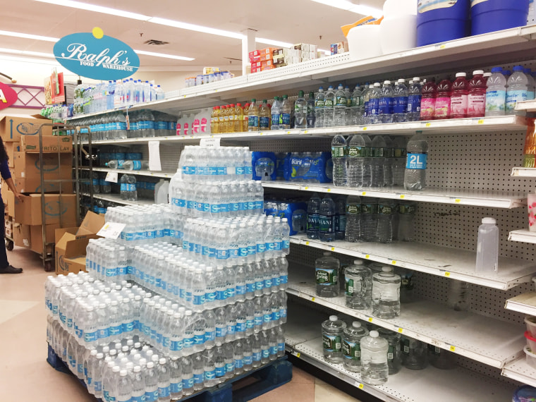 Image: Water bottles have been placed in front of partially empty shelves at Ralph's Supermarket in Gurabo, Costa Rica