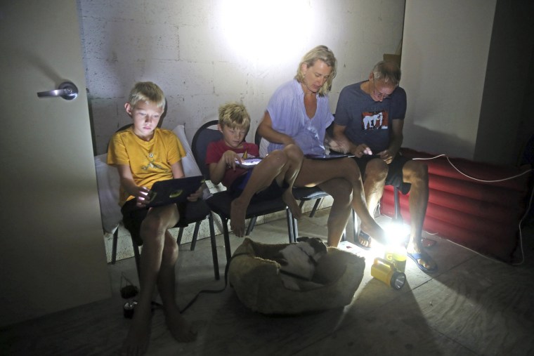 Image: The Blinckman family use their personal devices while sheltering in a stairwell utility closet as Hurricane Irma goes over Key West on Sept. 10.