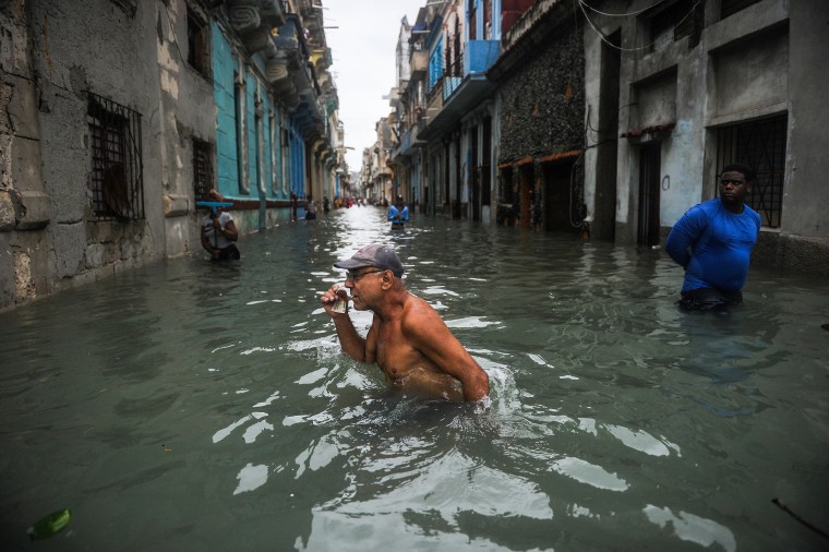 Image: A Cuban wades through a flooded street in Havana,