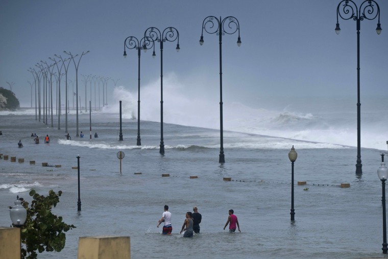 Image: Residents walk on Havana's sea wall as the ocean crashes into it, after the passing of Hurricane Irma in Havana