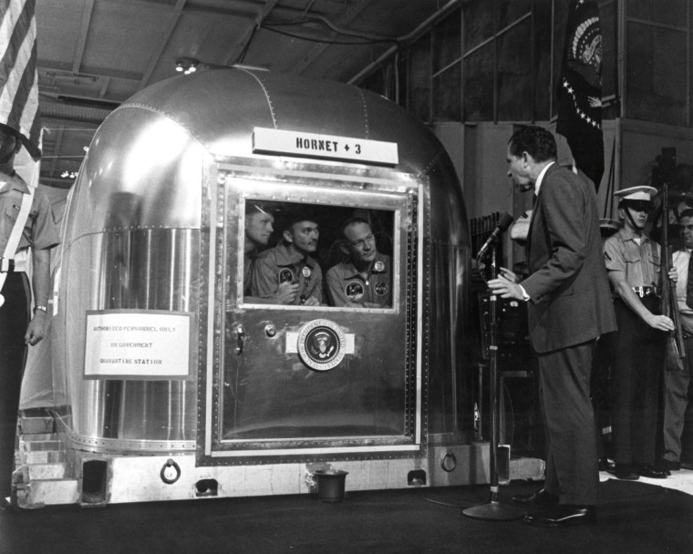 President Richard Nixon welcomes the returning Apollo 11 astronauts, from left, Neil Armstrong, Michael Collins and Edwin "Buzz" Aldrin Jr., still inside their quarantine unit aboard the USS Hornet on July 24, 1969.