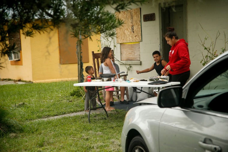 Image: With power out to her entire neighborhood and the surrounding area Marissa Calderon uses a gas grill to make scrambled eggs, hot dogs and tortillas for her brother and young cousins, in Bowling Green on Sept. 11.