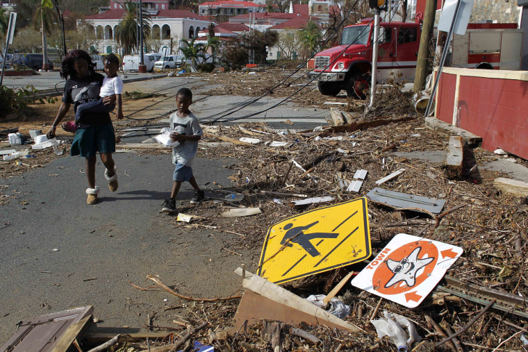 Image: A woman with her two children walk past debris left by Hurricane Irma in Charlotte Amalie, St. Thomas