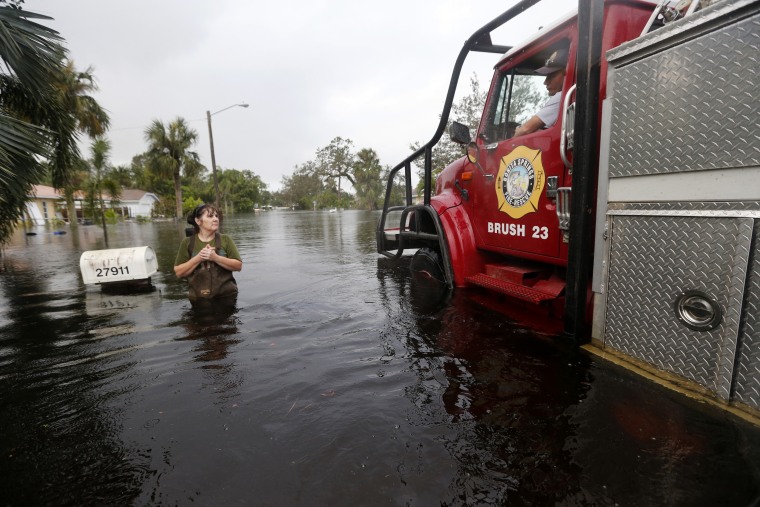 Firefighters check on Kelly McClenthen, who returned to check on the damage to her flooded home in Bonita Springs, Florida, on Monday in the wake of Hurricane Irma.