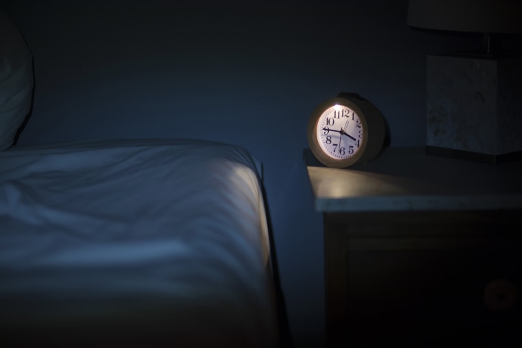 Image: An alarm clock sits on a bedside table