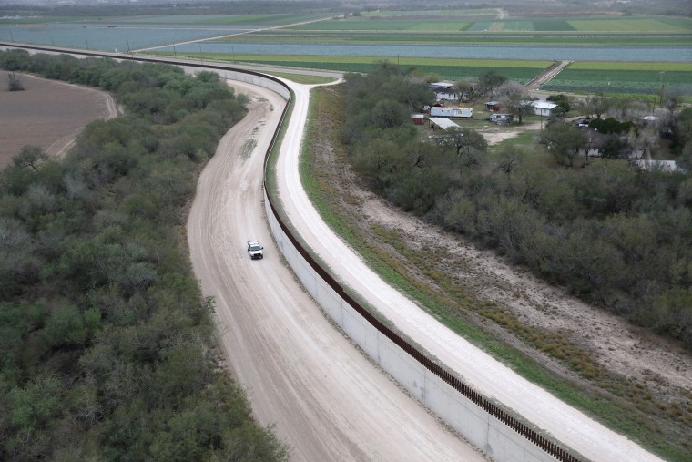 Image: A U.S. Border Patrol vehicle patrols next to a fence at the U.S.-Mexico border