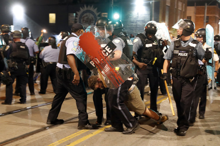 Image: Police arrest a man as they try to clear a violent crowd 