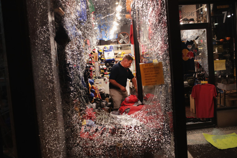 Image: A worker cleans up broken glass after a window was smashed