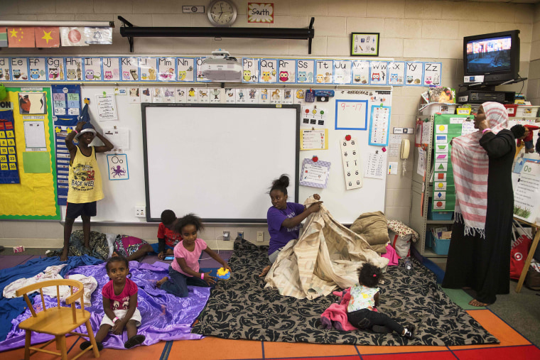 Image: A family makes sleeping arrangements in a classroom at a shelter within the Pizzo Elementary School in Tampa