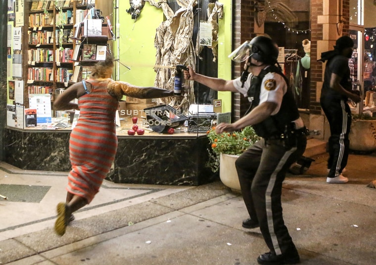 Image: A protester is sprayed with mace by riot police after throwing a chair through a window of a business during the second night of demonstrations.