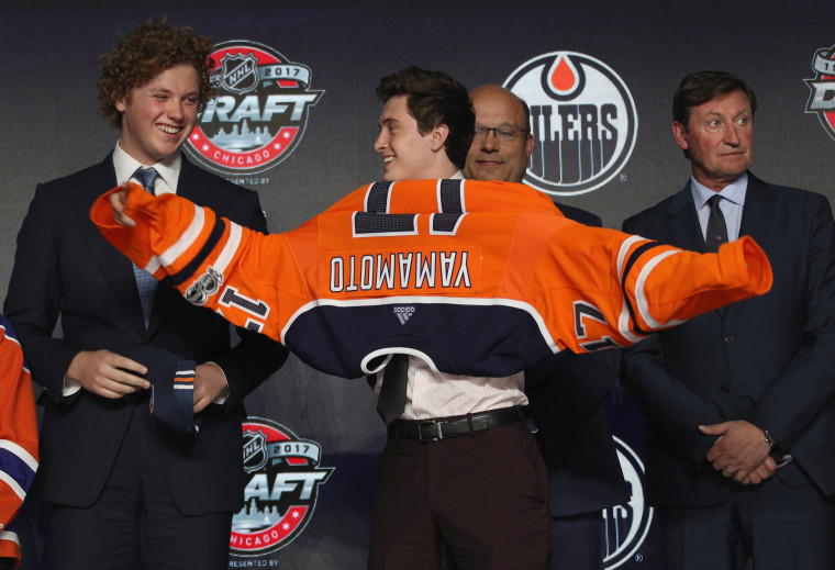 Image: Kailer Yamamoto puts on his jersey after being selected 22nd overall by the Edmonton Oilers during the NHL draft