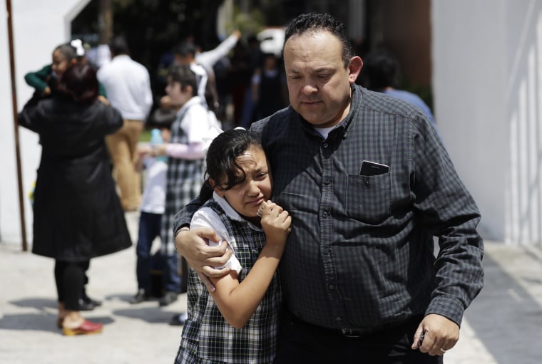 Image: A man comforts a frightened student as he picks her up from school in Mexico City's Roma neighborhood