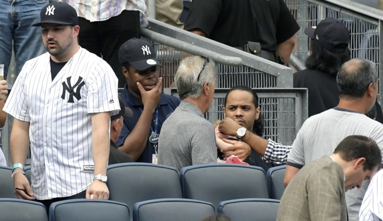 Image: Baseball fans reacts as a young girl is tended to before she is carried out after being hit by a line drive