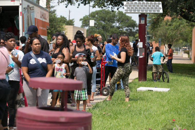 Hundreds of Hurricane Harvey victims brave the heat and wait in line to receive goods.