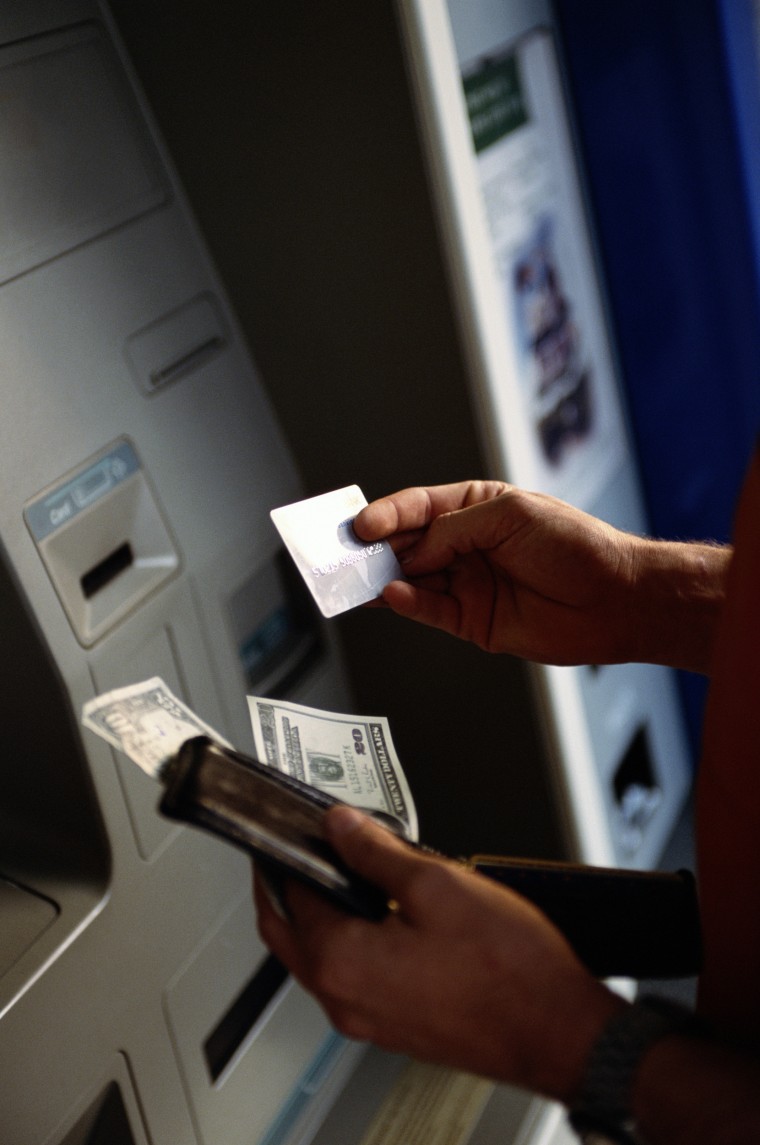Image: A man uses an ATM machine