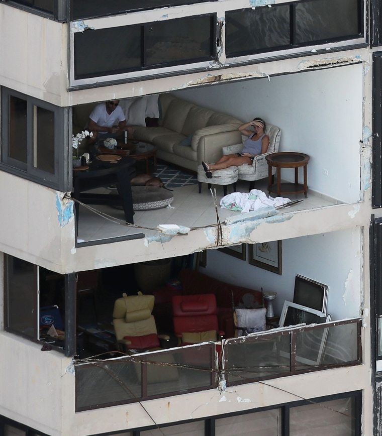 Image: People sit in their apartment with the window blown out in San Juan