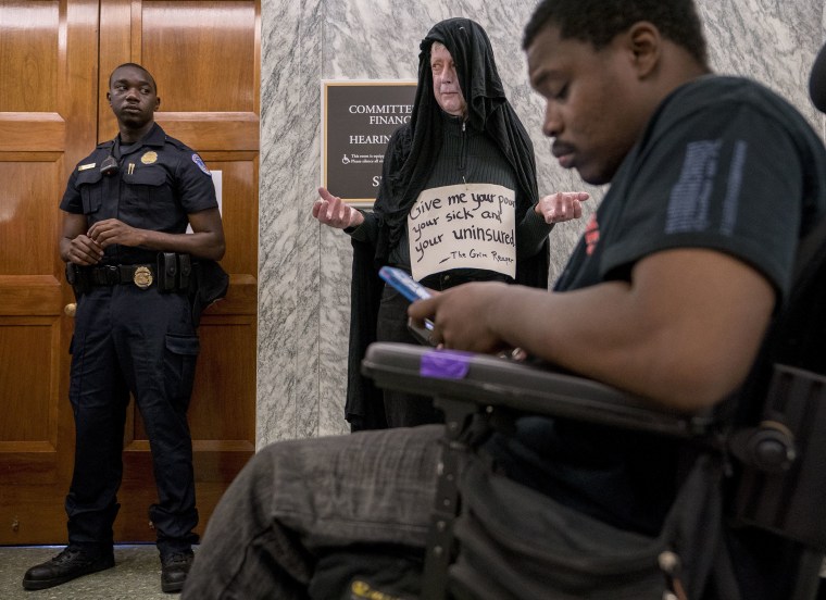 Image: David Barrows of Washington, center, dresses as the grim reaper and wears a sign that reads \"Give me your poor, your sick, and your uninsured\"