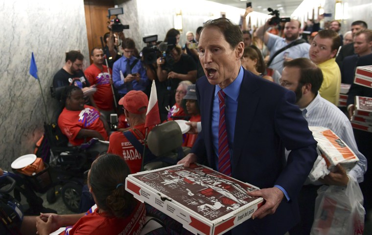 Image: Sen. Ron Wyden, D-Ore., carries pizza as he talks with people in wheelchairs